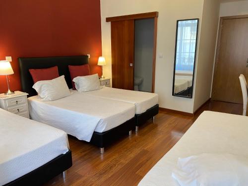 a hotel room with two beds and a mirror at Hotel Porto Rico in Porto