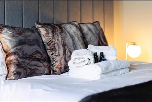 a pile of towels on a bed with pillows at Sweeney Motherwell in Motherwell
