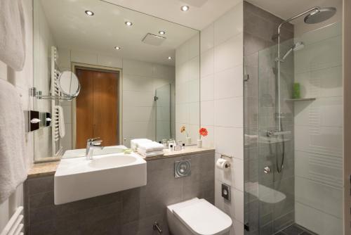 a bathroom with a sink and a toilet and a shower at Hotel Aquino Berlin in Berlin