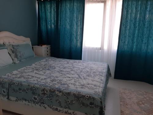 a bedroom with a bed with blue curtains and a window at Samlife Apart in Samsun