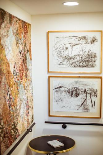a table in front of two paintings on a wall at The Negev Hotel By Domus in Beer Sheva