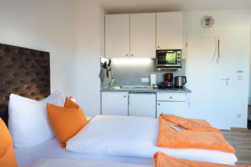 een wit bed met oranje kussens in een keuken bij H&H Apartments im Herzen der Stadt super zentral ruhig mit Kochnischen Balkon oder Empore in Greifswald