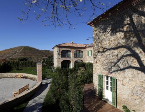 a large stone house with green shutters on it at Relais San Maurizio in Santo Stefano Belbo
