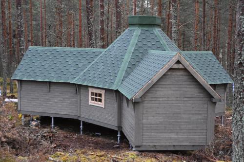 a small house with a green roof in the woods at Cairngorm Bothies in Aboyne