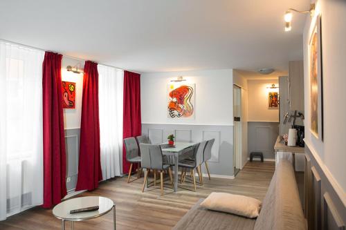 een woonkamer met een tafel en rode gordijnen bij H&H Apartments im Herzen der Stadt geräumig ruhig zentral mit Küche und Esstisch in Greifswald