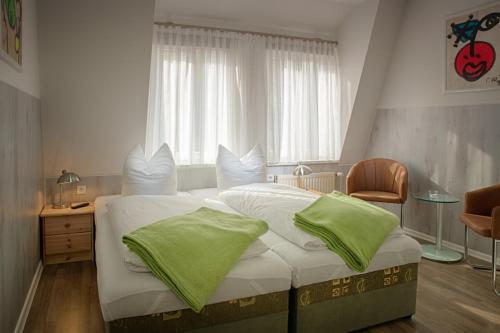 ein Schlafzimmer mit einem großen Bett mit grünen Kissen in der Unterkunft H&H Apartments im Herzen der Stadt in der Lange Strasse geräumig ruhig mit Küche und Esstisch in Greifswald