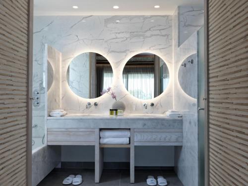 a bathroom with two sinks and two mirrors at Atlantica Dreams Resort in Gennadi