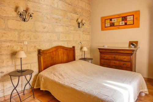 a bedroom with a bed and a stone wall at Au Saint Roch - Hôtel et Jardin in Avignon