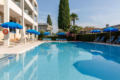 a large swimming pool with blue umbrellas and chairs at Hotel Idania in Bardolino