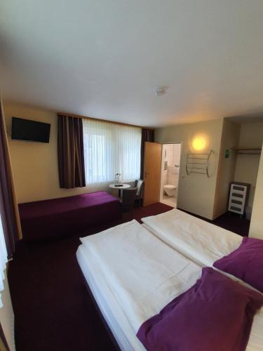 a bedroom with a large white bed with purple pillows at Hotel Bergschlösschen in Boppard
