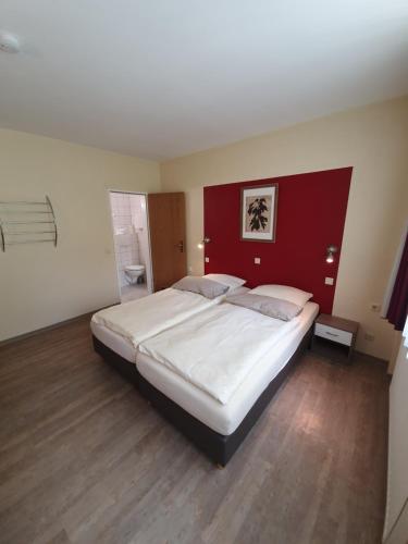 a bedroom with a large bed with a red headboard at Hotel Bergschlösschen in Boppard