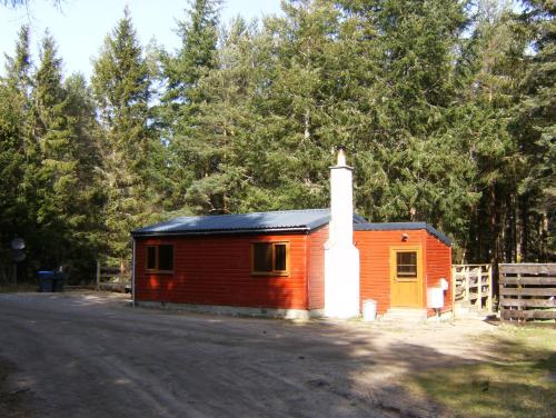 a small red building with a white chimney on a road at Cairngorm Lodges in Aboyne