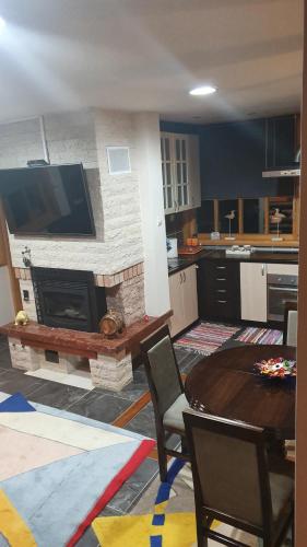 ein Wohnzimmer mit einem Tisch und einem Fernseher an der Wand in der Unterkunft Vila Panić Zlatibor in Zlatibor