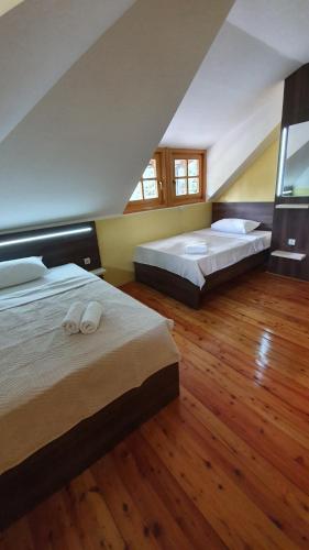 2 Betten in einem Schlafzimmer mit Holzböden und Fenstern in der Unterkunft Vila Panić Zlatibor in Zlatibor