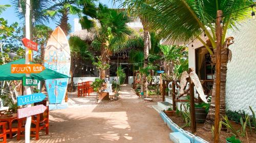 un complexe avec des tables, des chaises et des palmiers dans l'établissement Sirenas Caribbean Rooms Holbox, à Holbox