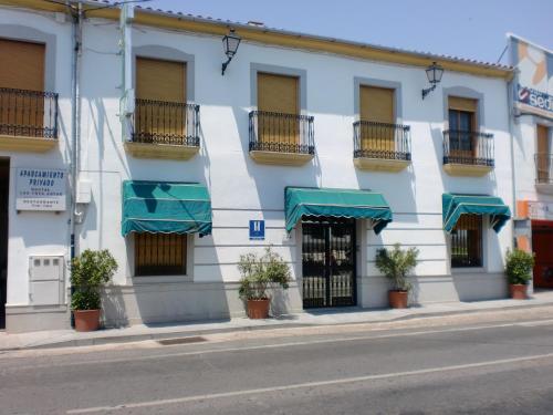 un bâtiment blanc avec des auvents verts dans une rue dans l'établissement Hostal las Tres Jotas, à Alcaracejos