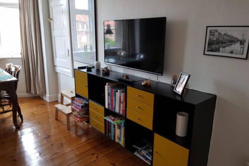 uma sala de estar com um centro de entretenimento com uma televisão de ecrã plano em Dejlig lejlighed først for på Amager em Copenhague