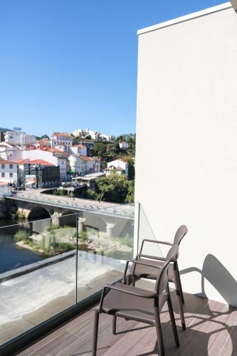 a chair on a balcony with a view of a city at Hotel Vouga in Termas de Sao Pedro do Sul
