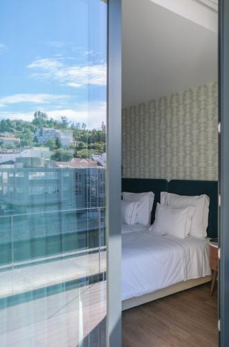a bedroom with a bed and a large window at Hotel Vouga in Termas de Sao Pedro do Sul