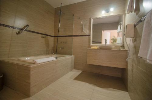 een badkamer met een bad, een wastafel en een spiegel bij El Angolo Piura in Piura