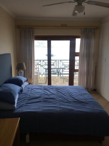 Un dormitorio con una cama azul con vista al mar. en Laguna Grove 50 3 bedroom, en Knysna