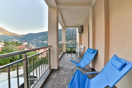 a balcony with blue chairs and a view of the water at Java Apartments in Dobrota