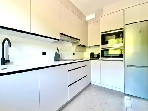 una cocina blanca con armarios y electrodomésticos blancos en El Mirador de Merón, en San Vicente de la Barquera