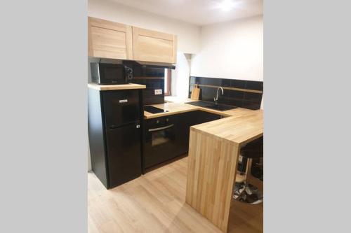 - une cuisine avec des appareils noirs et des armoires en bois dans l'établissement Atelier du 7, à Bouzigues