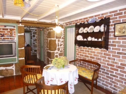 a dining room with a table and chairs and a brick wall at Casa do Tamanqueiro in Estorãos