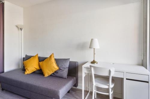 a couch with yellow pillows sitting next to a desk at Studio with terrace close to the Prado beach in Marseille Welkeys in Marseille