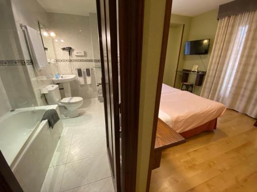 a room with a bathroom with a bed and a tub at Hostal Concejo in Salamanca