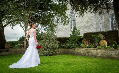a woman in a wedding dress standing in the grass at Old Ground Hotel in Ennis