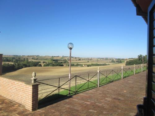 a fence with a light pole and a field at camere in Villa Luzi in Treia