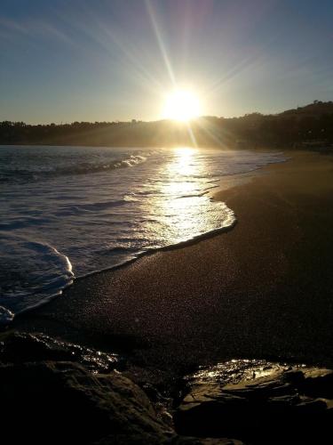 a beach with the sun shining on the water at Hotel Ariston & Apartments in Varazze