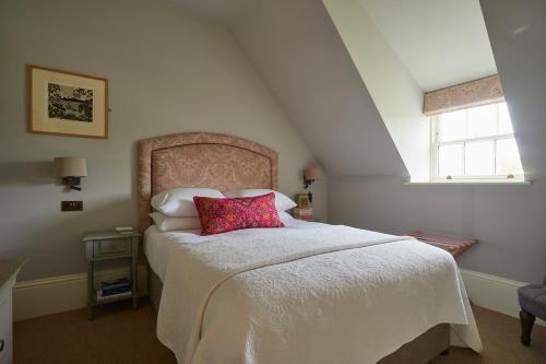 ein Schlafzimmer mit einem Bett mit einem roten Kissen darauf in der Unterkunft The White House in Burnham Market