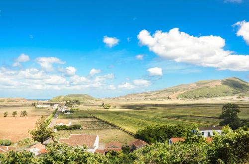 a view of a farm with mountains in the background at Quinta dos Frutos in Santa Cruz da Graciosa