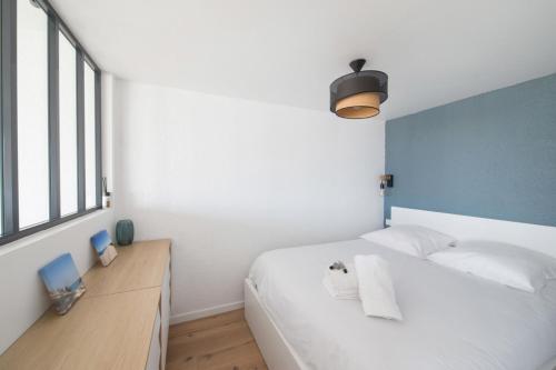 une chambre avec un lit blanc et une grande fenêtre dans l'établissement Appartement de la Jetée - Welkeys, à Arcachon