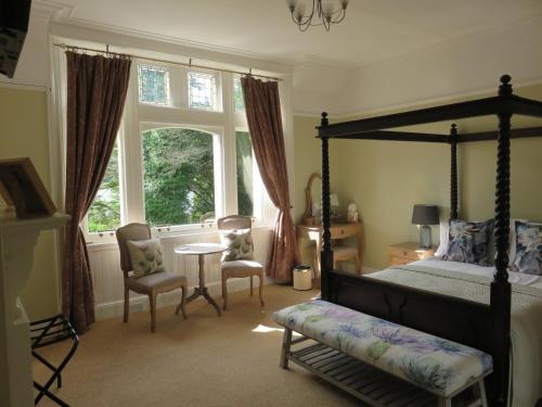 a bedroom with a canopy bed and a table and chairs at Ravenswood House B&B in Fort William