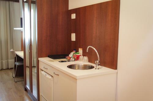 a kitchen counter with a sink and a mirror at Bristol Centro Civico Curitiba in Curitiba
