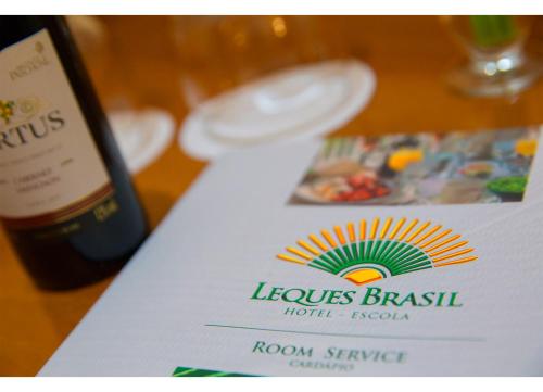 a bottle of wine sitting next to a table with a paper at Leques Brasil Hotel Escola in Sao Paulo