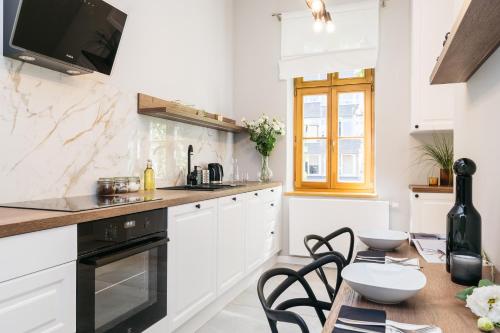eine Küche mit weißen Schränken und einem Tisch mit Stühlen in der Unterkunft Papillon Apartment by LoftAffair in Krakau