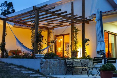 a house with a patio with chairs and an umbrella at Casa Limonina in Louriçal