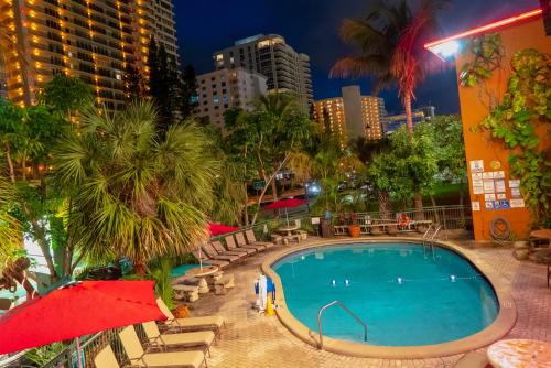 a swimming pool with chairs and a red umbrella at Ft. Lauderdale Beach Resort Hotel in Fort Lauderdale