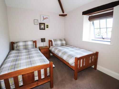 1 dormitorio con 2 camas y ventana en Carleton Mill Cottage, en Carlisle