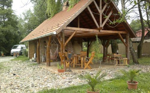 a pavilion with a table and chairs in a backyard at Folyóka Vendégház in Egyházasgerge