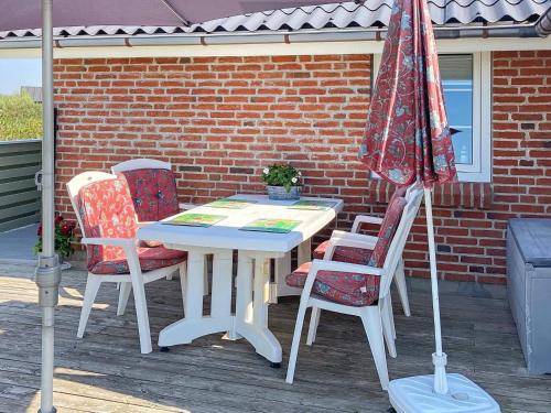 una mesa y sillas con una sombrilla en el patio en 6 person holiday home in R m en Lakolk