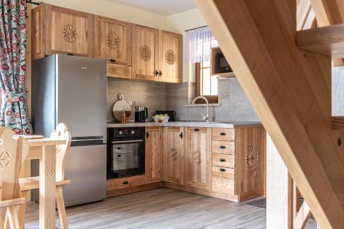 a kitchen with wooden cabinets and a stainless steel refrigerator at Osada LUX-HOUSE & SAUNA in Zakopane