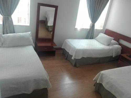 a hotel room with two beds and a mirror at Hotel Bella Montaña in Manizales