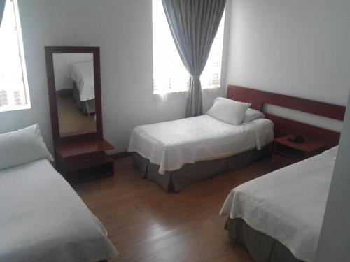 a hotel room with two beds and a mirror at Hotel Bella Montaña in Manizales