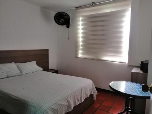 a bedroom with a bed and a window with a blind at Hotel 42 Avenida in Palmira